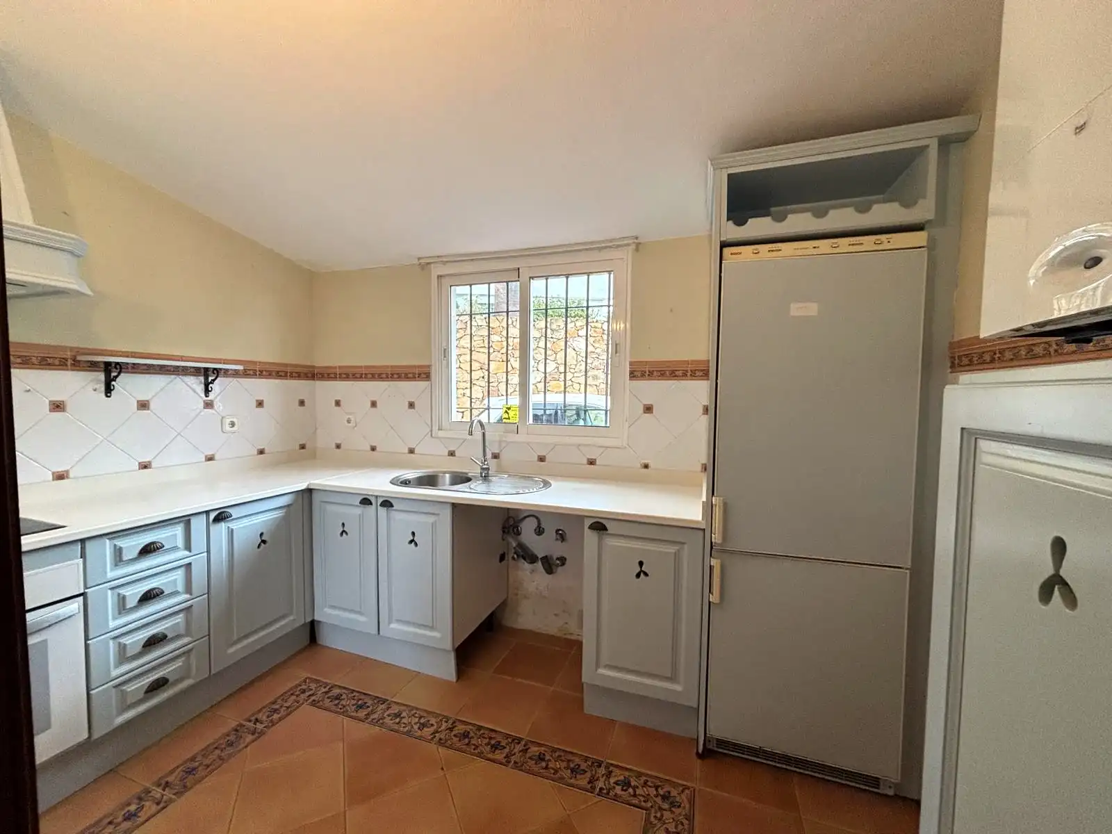 Separate Küche mit Außenfenster, Spüle unter dem Fenster und hellen Möbeln.