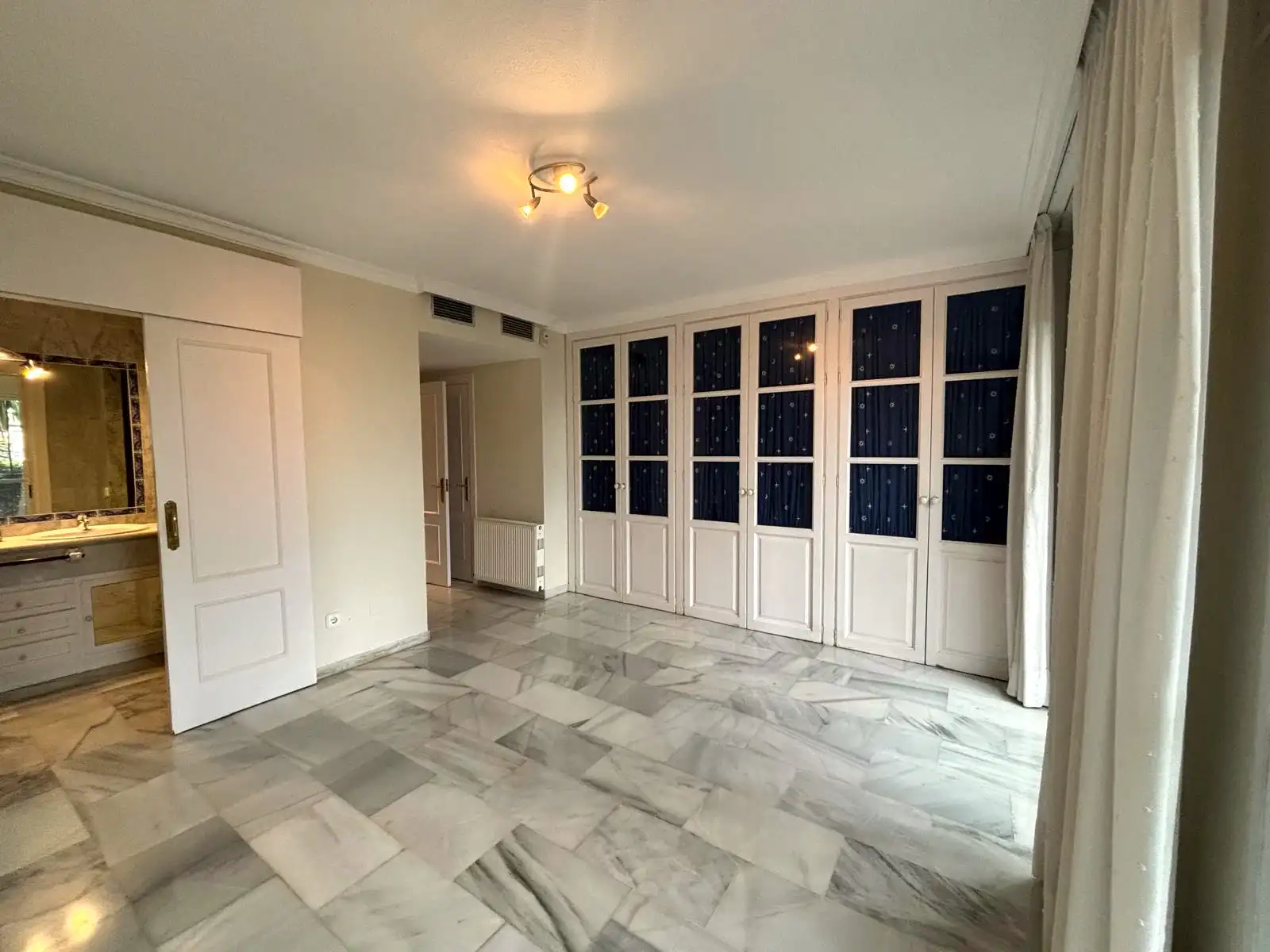 Schlafzimmer mit großer Einbauschrankfront und sichtbar integriertem Bad im Hintergrund in Brisas II, Manilva.