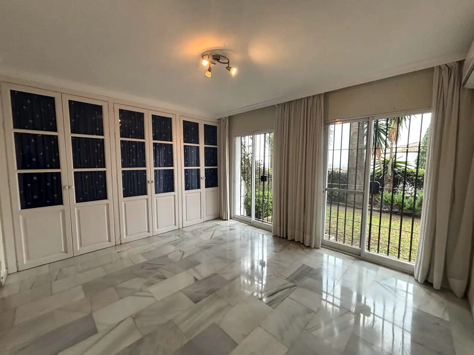 Bedroom with wall-to-wall wardrobes and large windows towards the garden in Brisas II, Manilva.