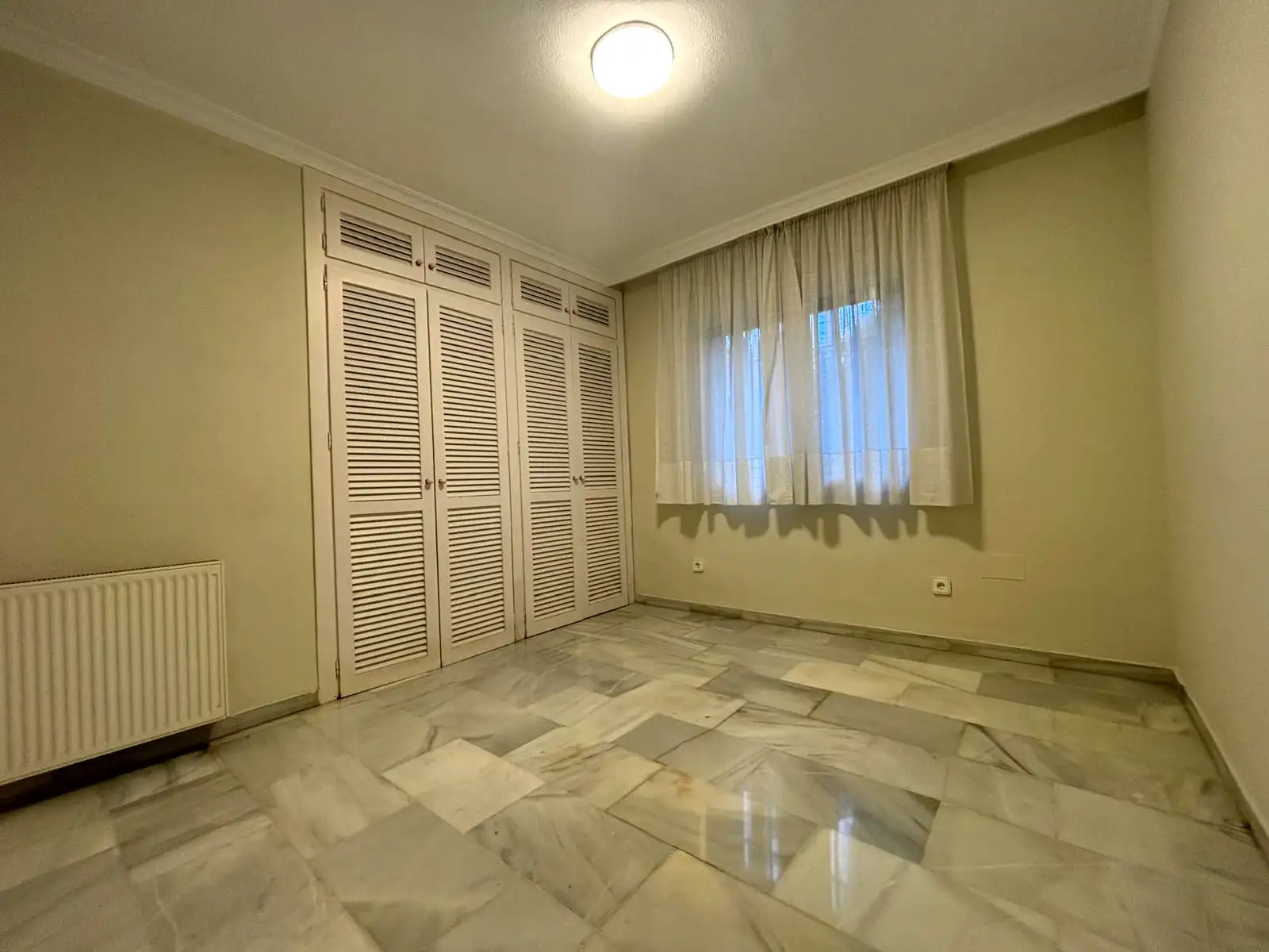 Schlafzimmer mit Lamellenschränken, Außenfenster und Marmorboden in Brisas II, Manilva.