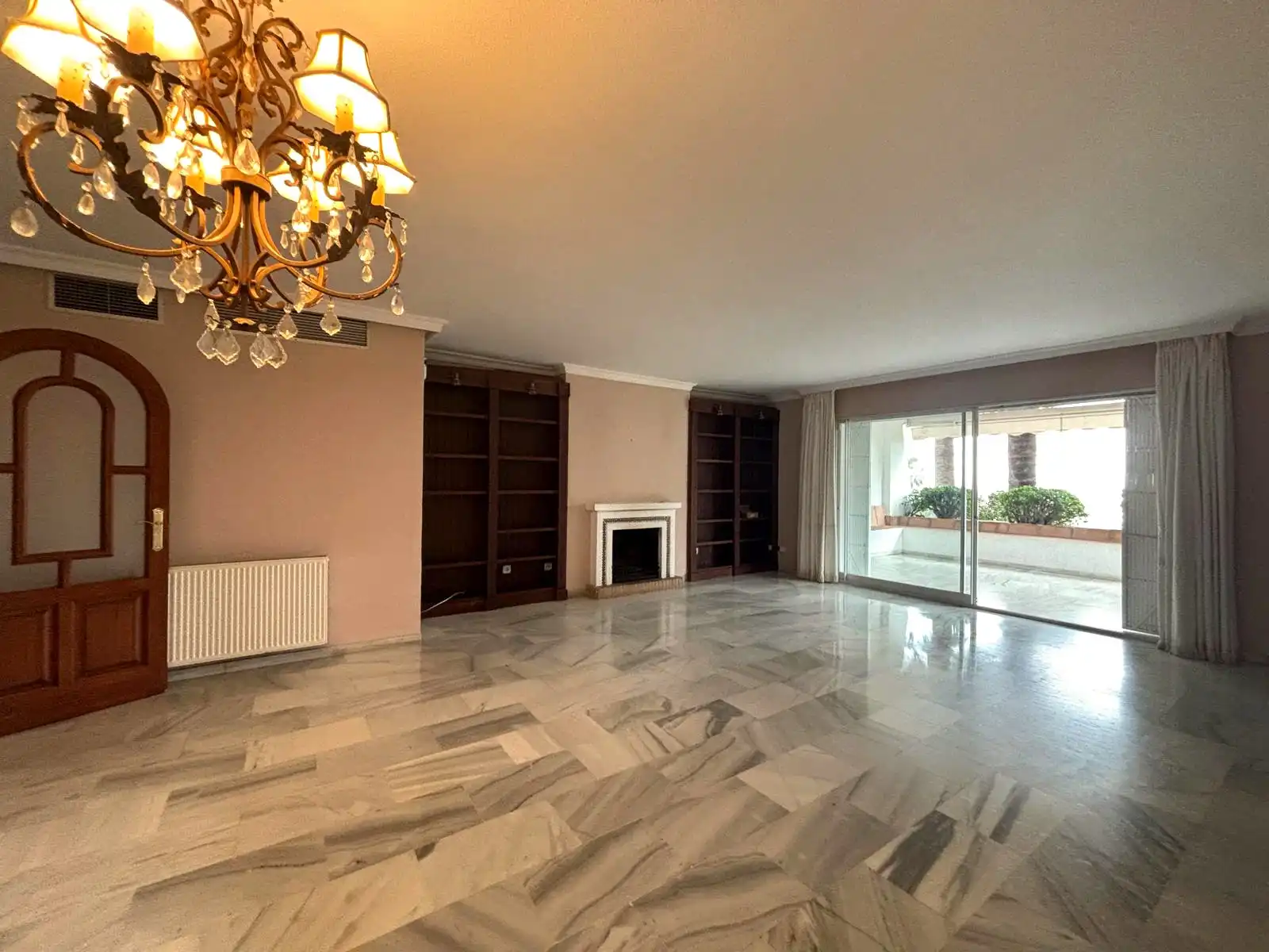 Spacious living and dining room with marble floors, fireplace and access to the covered terrace in Brisas II, Manilva.