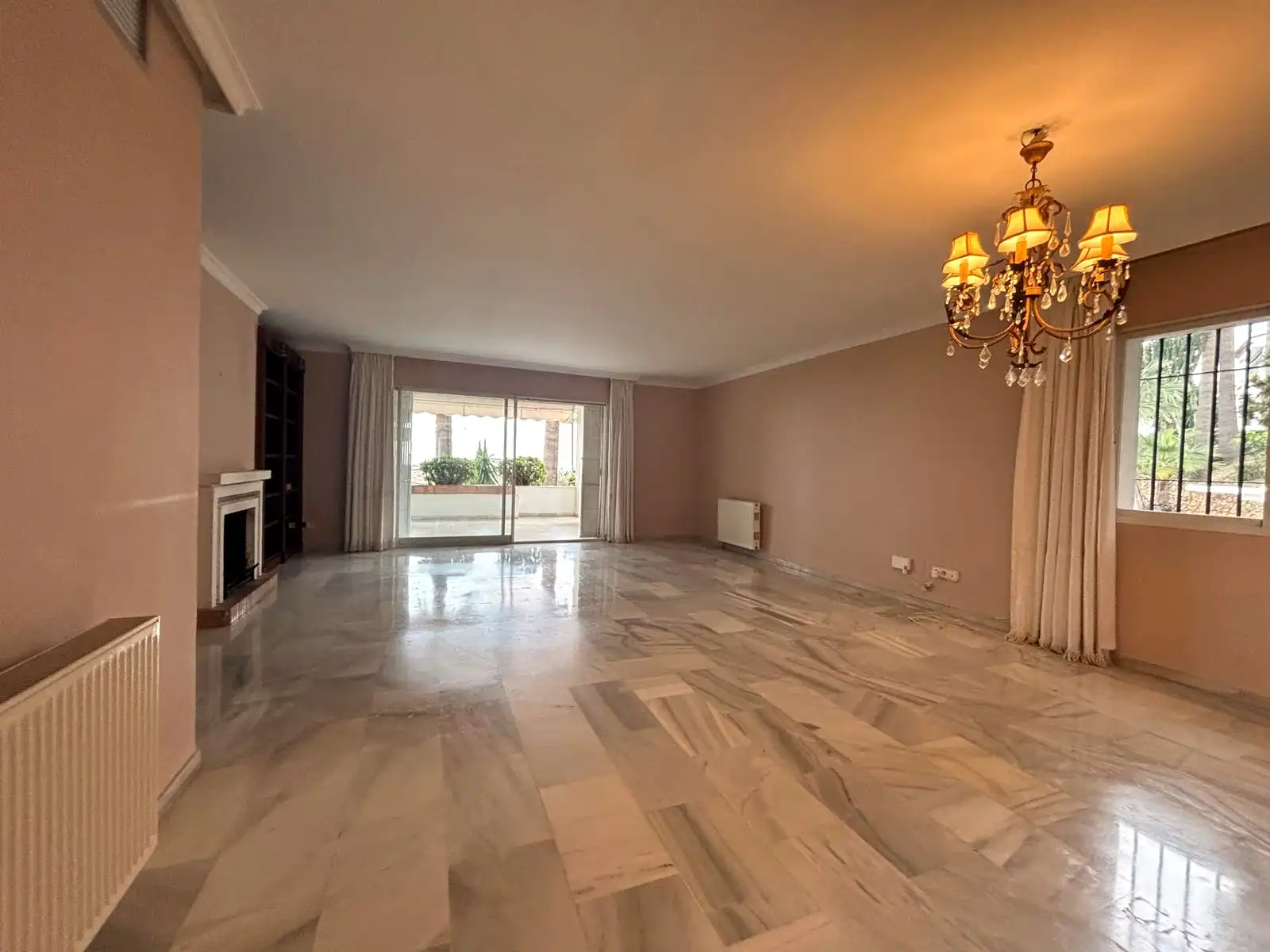 Großer Wohn-Essbereich mit Marmorböden, Kamin und Blick zur überdachten Terrasse in Brisas II, Manilva.